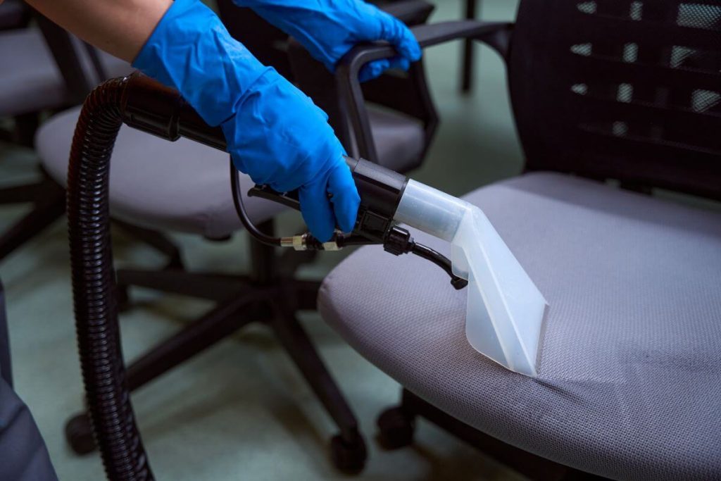 Technician performing commercial upholstery cleaning with a professional extractor